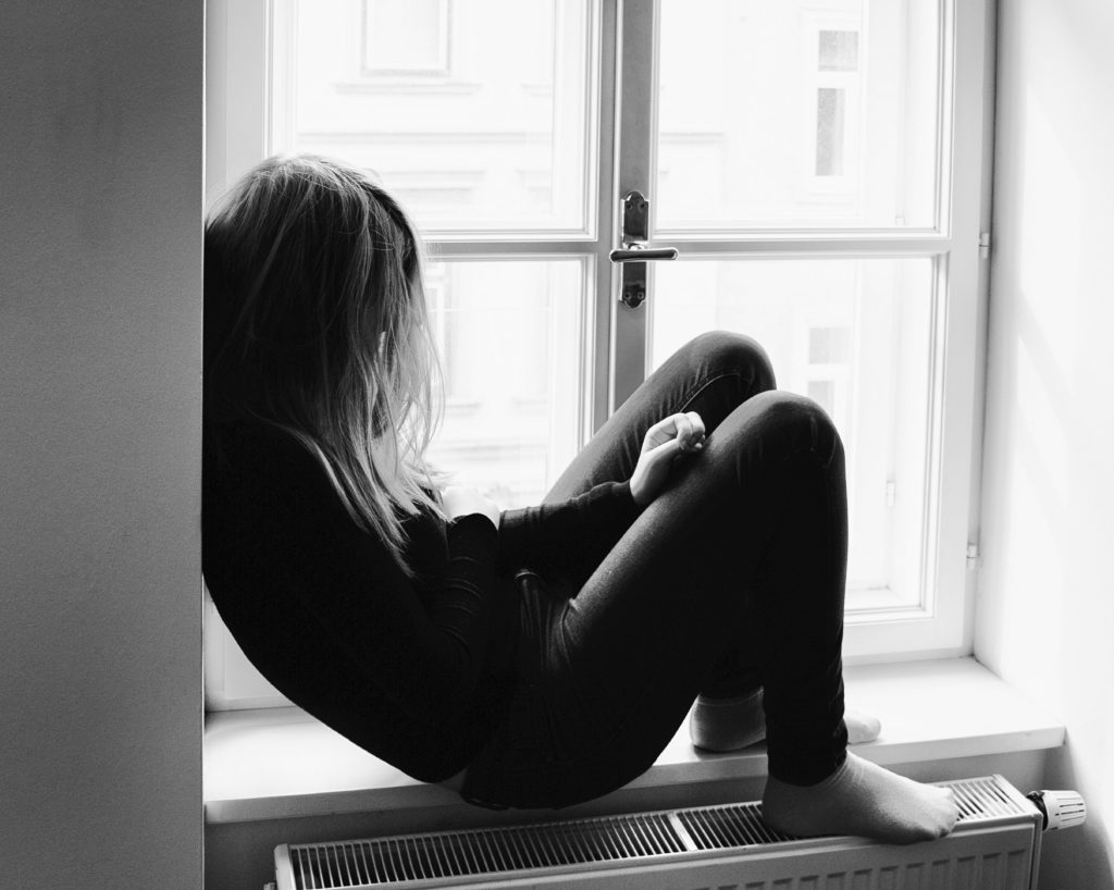 Sad teenager sitting by a window
