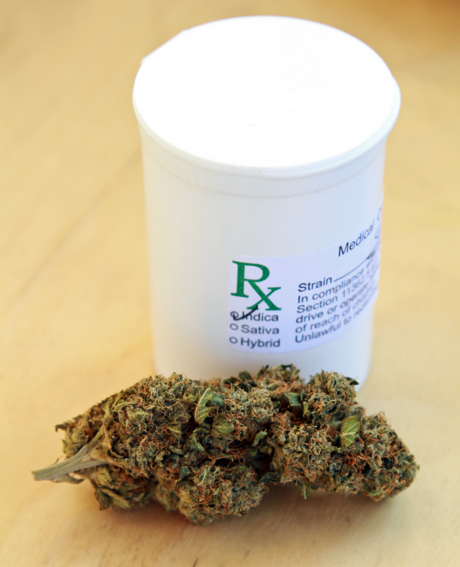 An RX medicine bottle sitting on a table next to some marijuana