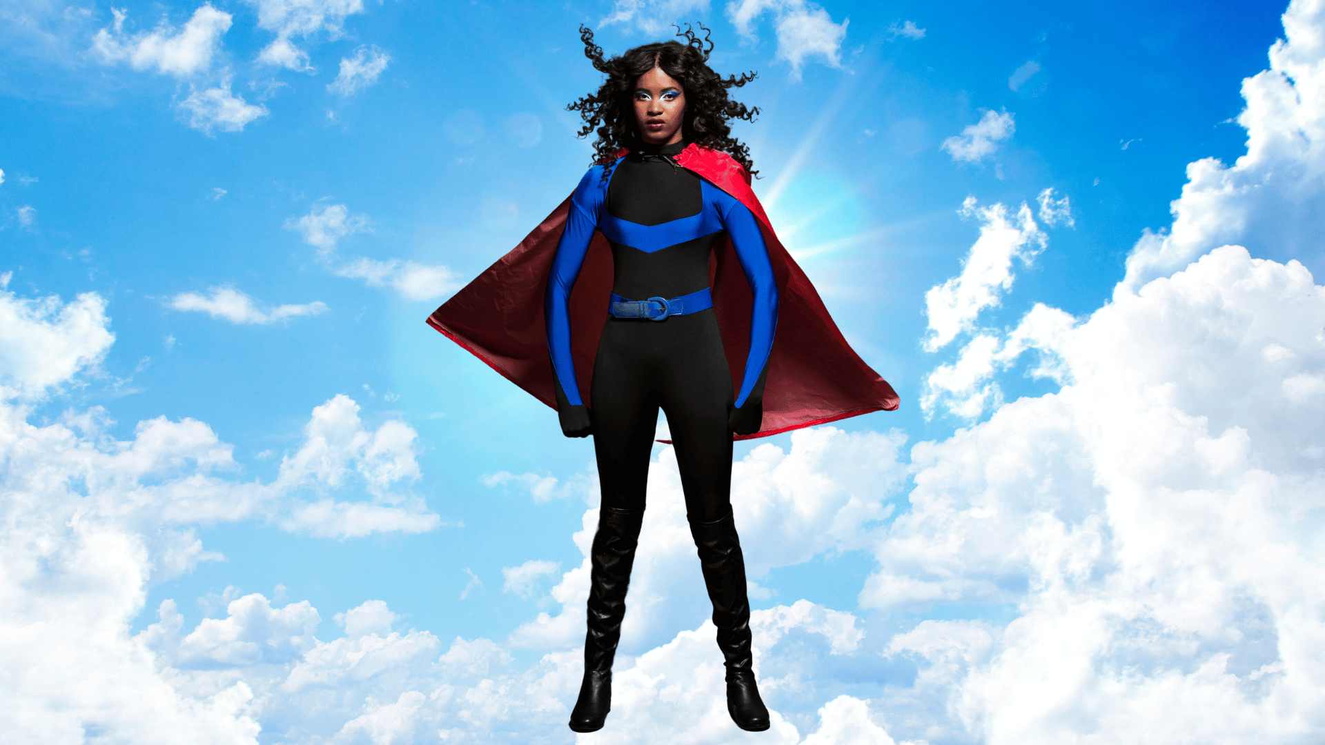 A Black woman, dressed in a superwoman costume, standing proud against a bright blue sky